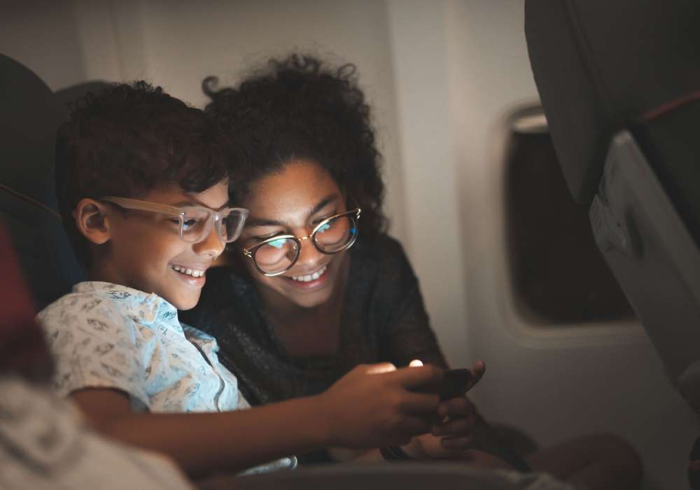 Two people looking at a phone on the airplane.